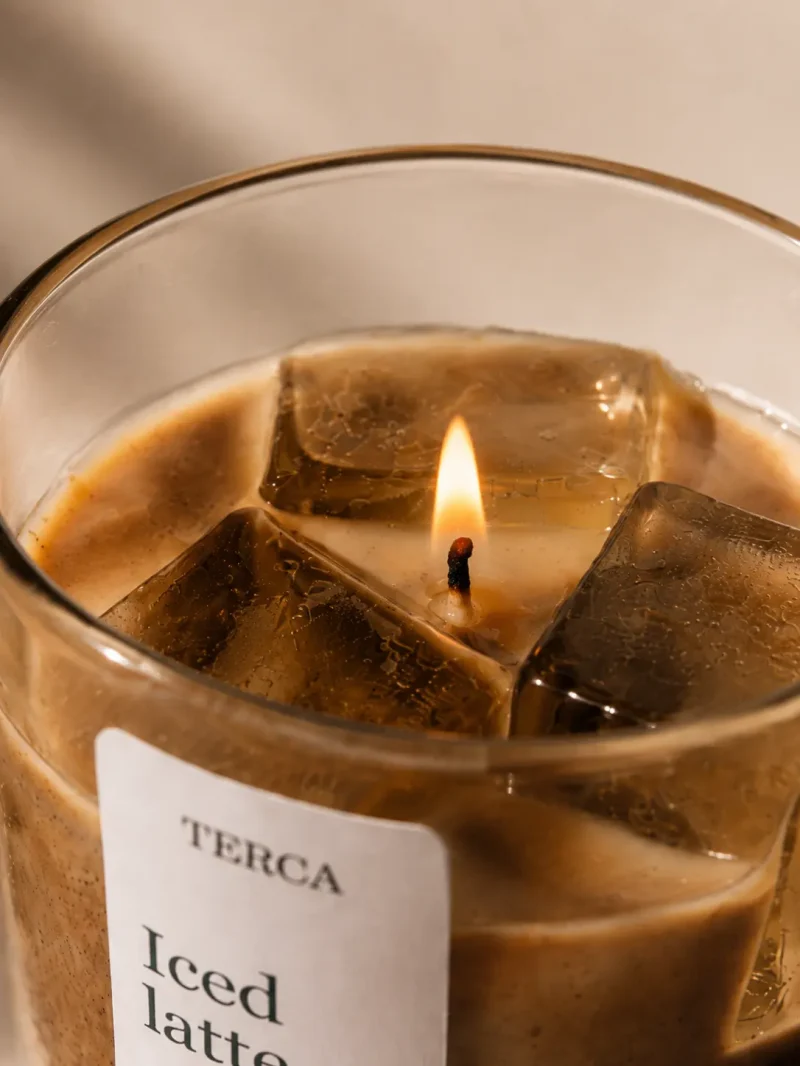 Vela TERCA Iced Latte encendida, en primer plano, con la llama entre los cubos de cera