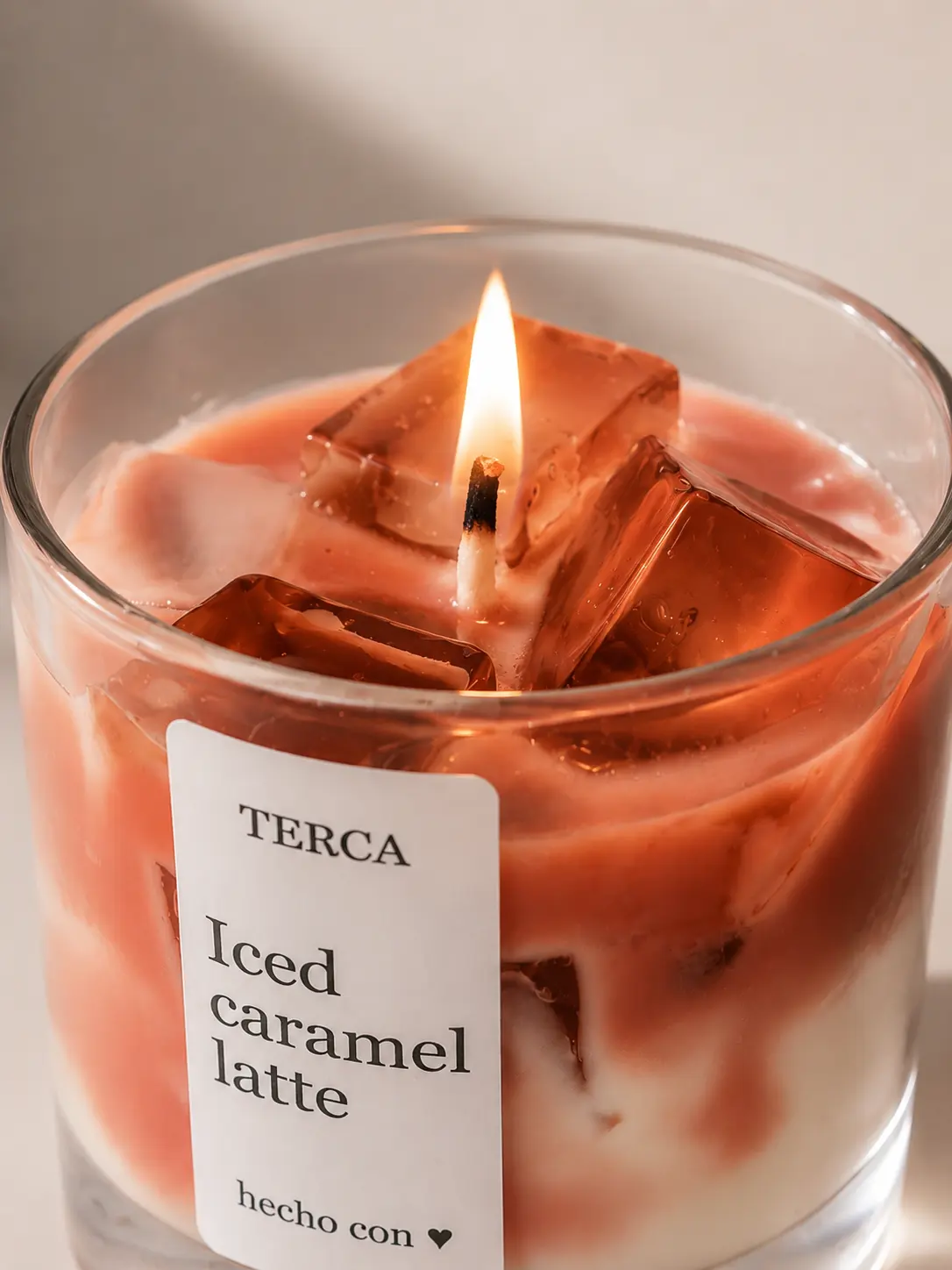 Vela TERCA Iced Caramel Latte encendida, con luz cálida alrededor